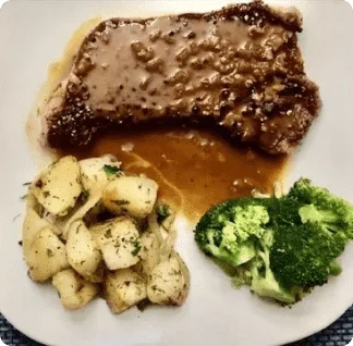 A white plate topped with meat, potatoes and broccoli