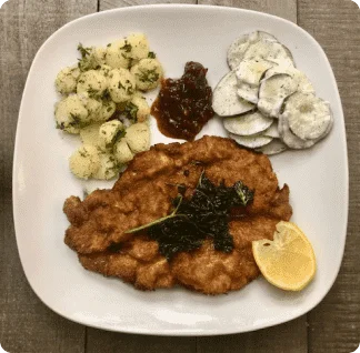 A white plate topped with fried meat and veggies