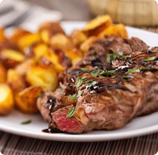 A white plate topped with steak and potatoes